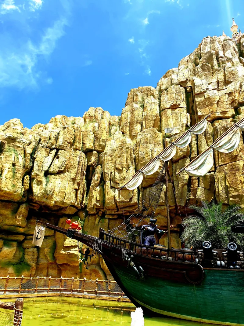A pirate ship with cannons and sails sits beside an artificial rocky cliff at a theme park in Phu Quoc.