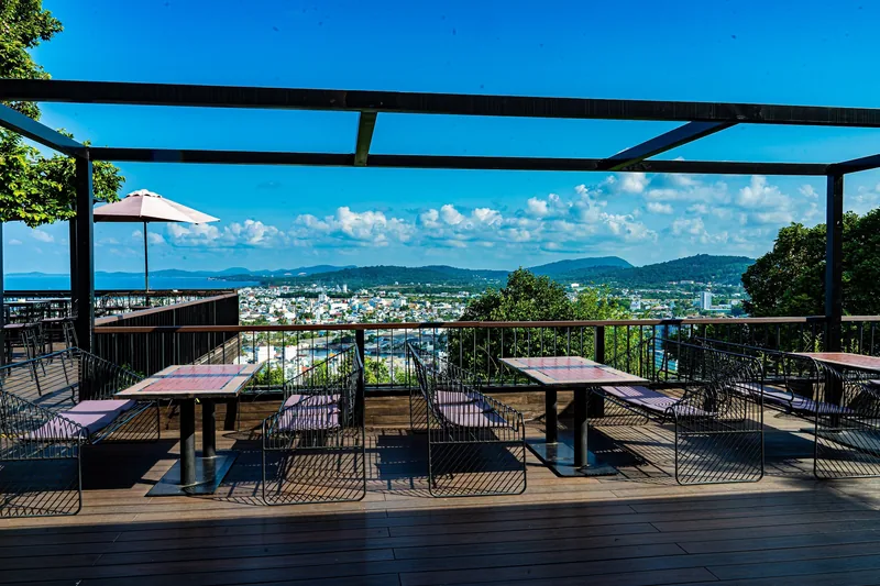 An open-air rooftop cafe terrace overlooks the sprawling town and hills of Phu Quoc under a bright blue sky.