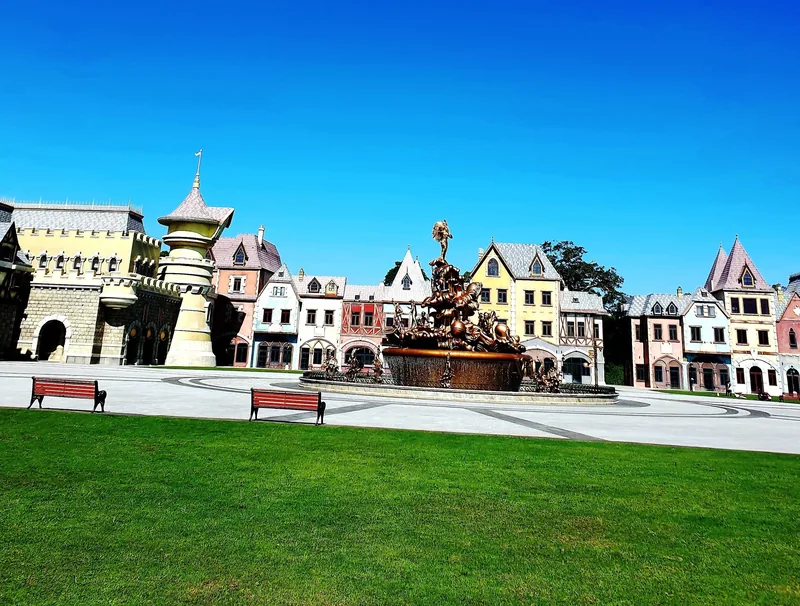 A European-style plaza with colorful gabled houses and a bronze fountain under a clear blue sky in Phu Quoc.