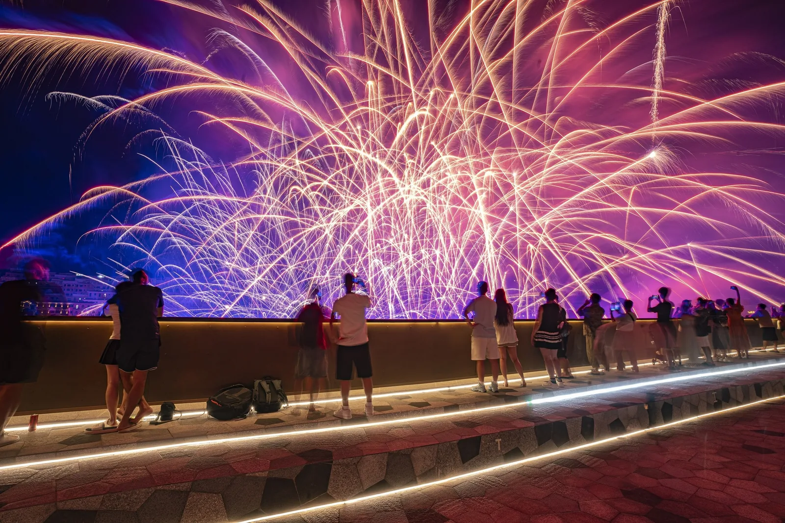 Crowds watch a vivid fireworks display over the water from Kiss Bridge in Phu Quoc at night.