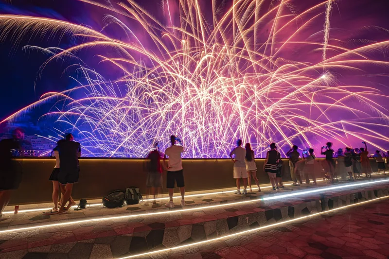 Crowds watch a vivid fireworks display over the water from Kiss Bridge in Phu Quoc at night.